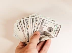 a hand holding a bundle of twenty dollar bills